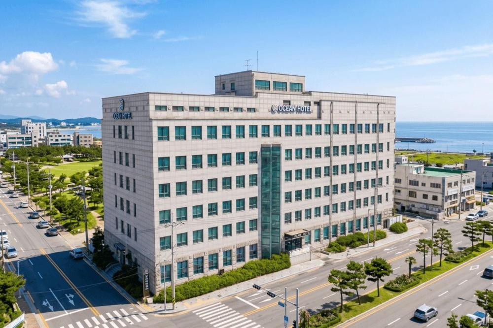a large white building on a street next to a road at Ocean Hotel Pohang in Pohang
