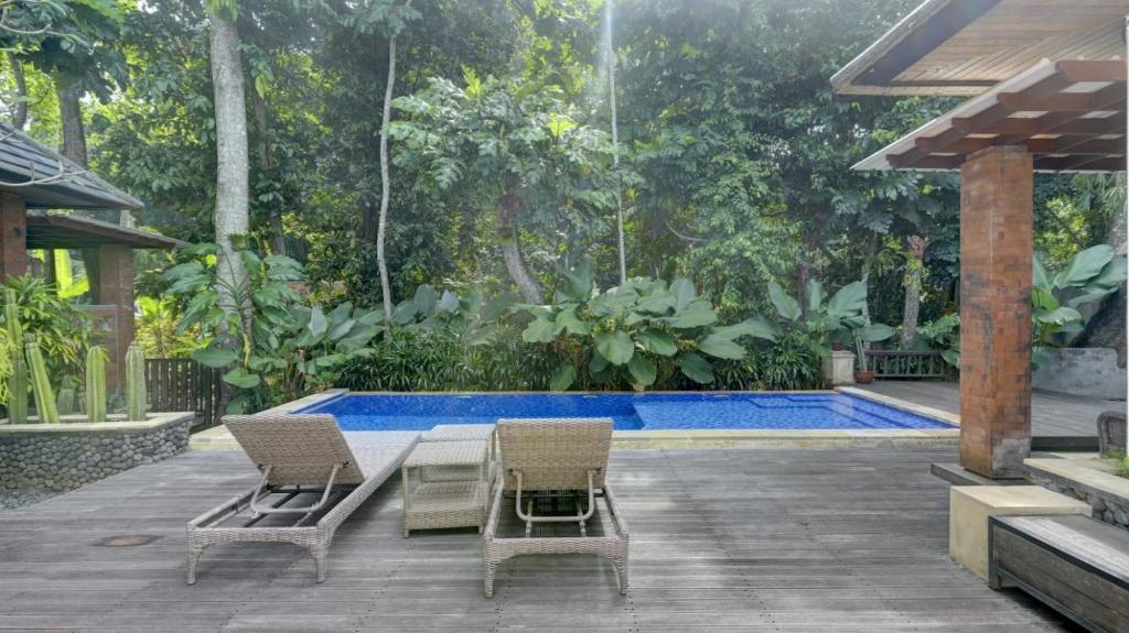 a patio with two chairs and a table and a pool at Villa Maeni in Munggu