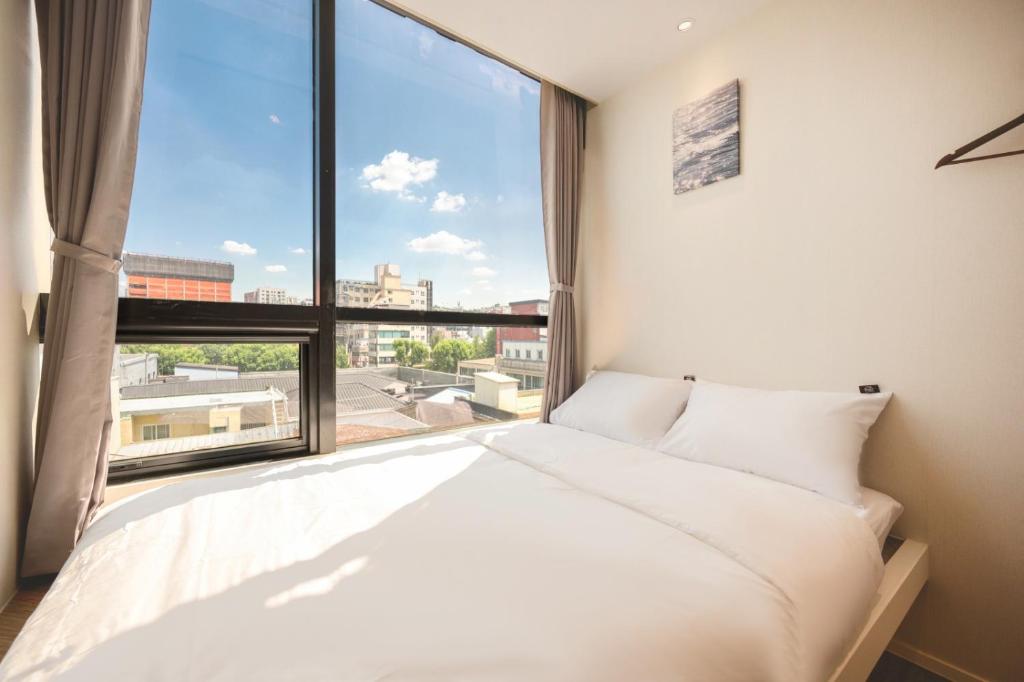a bedroom with a bed and a large window at Mumum Jongno in Seoul