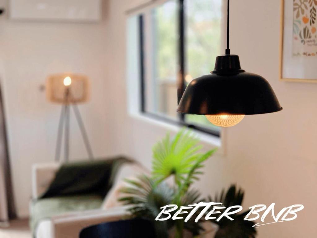 a black lamp hanging in a living room with a couch at Quiet Haven Retreat | Cozy Modern Townhouse in Lower Hutt