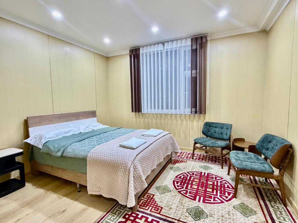 ein Schlafzimmer mit einem Bett und zwei Stühlen und einem Teppich in der Unterkunft Sunpath Mongolia Tour & Hostel in Ulaanbaatar