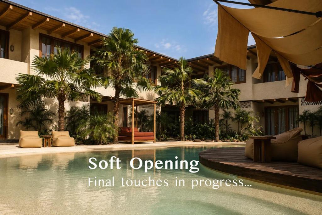 a pool in front of a building with palm trees at Kumbara Oasis Lombok in Kuta Lombok
