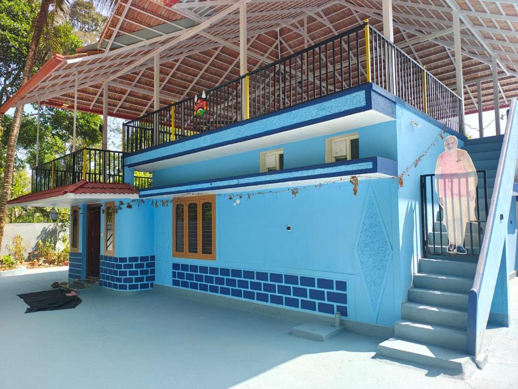 a blue house with a staircase in front of it at Tranquil Breeze Stay in Napoklu
