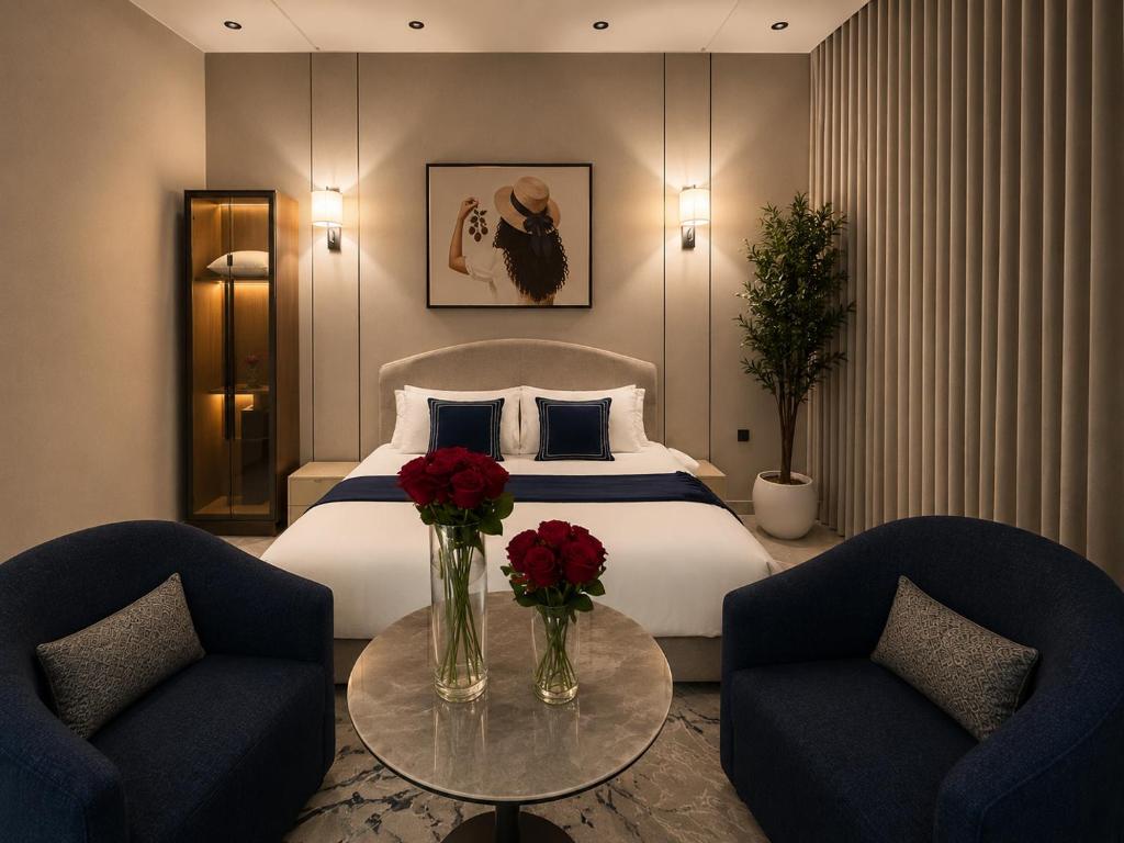 a hotel room with a bed with two chairs and a table with roses at Toot Suites Studio in Abha