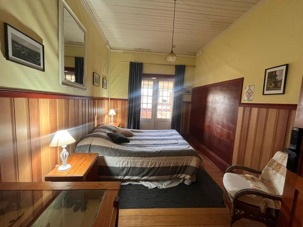 a bedroom with a bed and a table and a chair at Amura Hostel in Puerto Varas