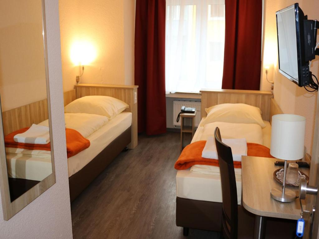a hotel room with two beds and a television at Hotel Paris in Düsseldorf