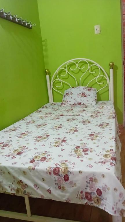 a green bedroom with a bed with a floral bedspread at Hospedaje restaurant Sr de Sipan in Sipán