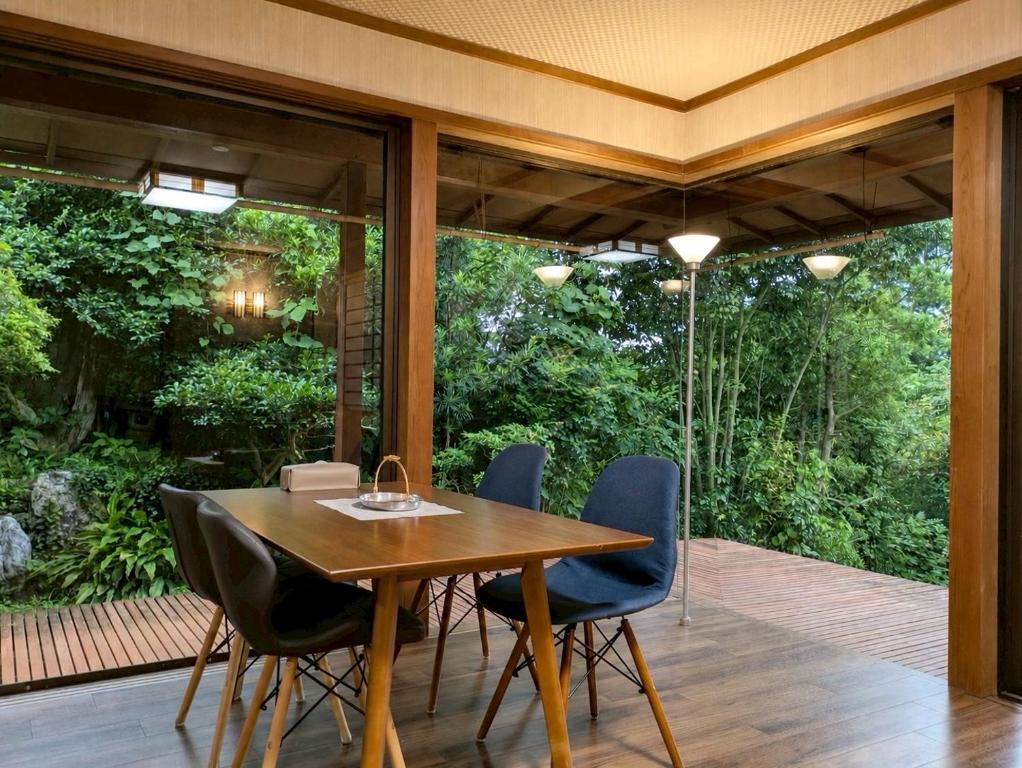 a dining room with a table and chairs on a deck at 春まち in Ito