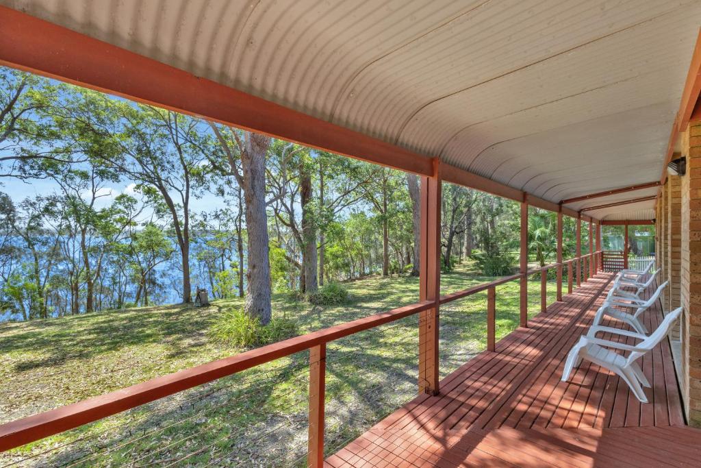 a wrap around porch with white chairs on it at Sunset Nest No 1 in Sanctuary Point