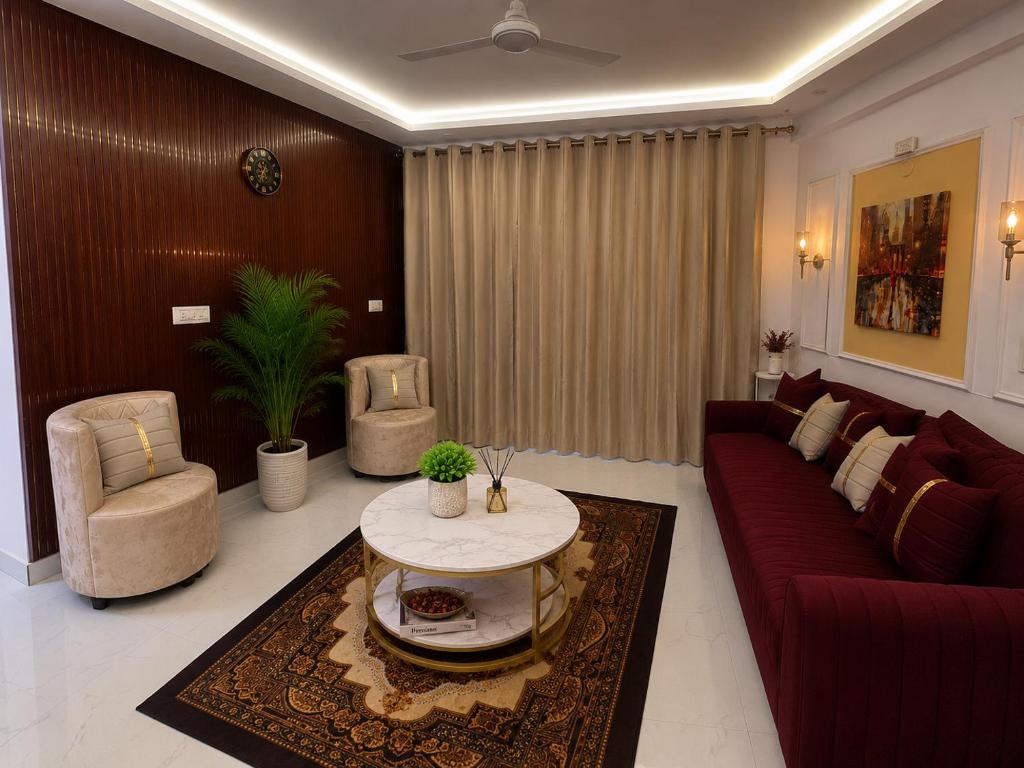 a living room with a red couch and a table at Riwaayat & Wings, a luxe stay 5 min from Taj Mahal in Tājganj