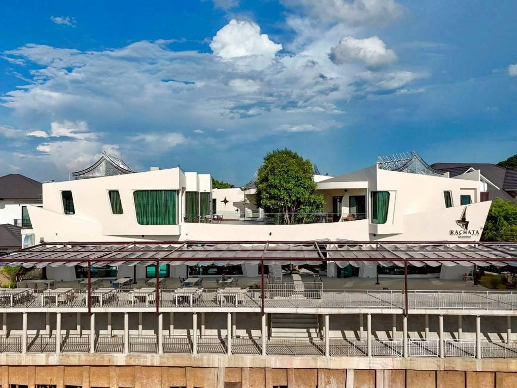 a white building with tables and chairs in front of it at The Rachata at Ayothaya in Ban Khlong Takhian