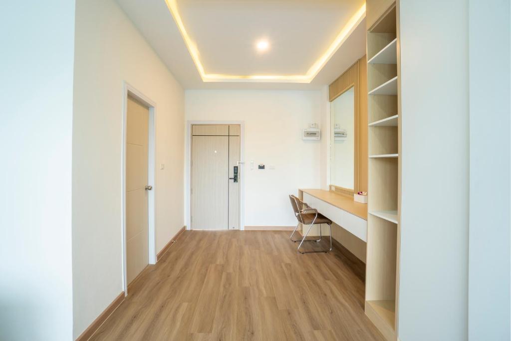 A bright guest room entry area with a long desk, chair, shelving, and closet.