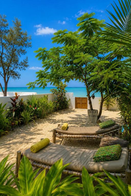two benches on a beach with the ocean in the background at Kita Ocean House in Kiwengwa