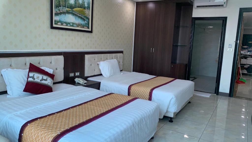 a hotel room with two beds and a bathroom at Khách sạn Rosy in Hòa Ðình