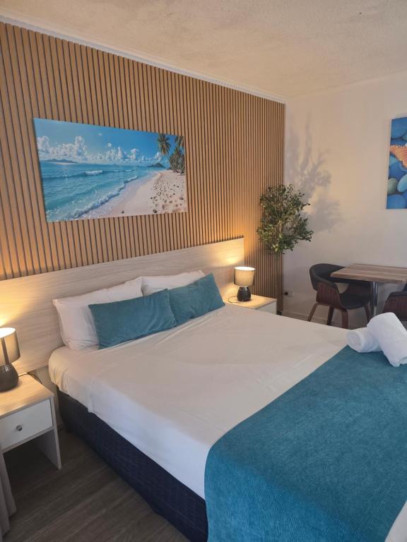 a hotel room with a large bed and a table at Alexandra Park Motor Inn in Bundaberg