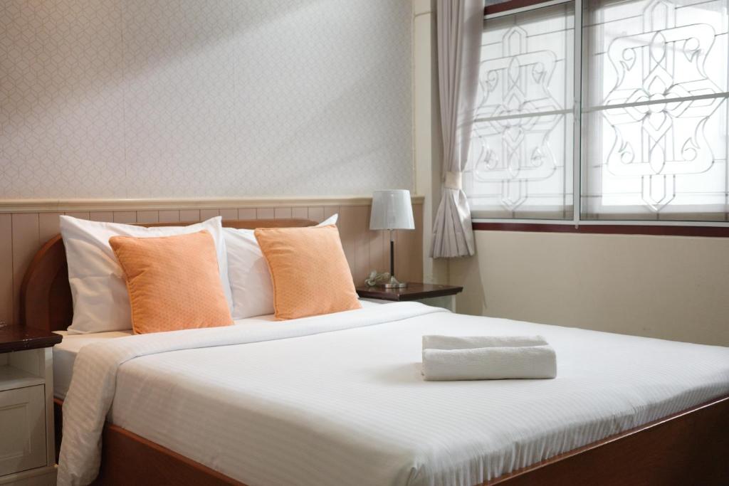 a bedroom with a large bed with orange pillows and a window at โรงแรมยุติชัย in Prachuap Khiri Khan