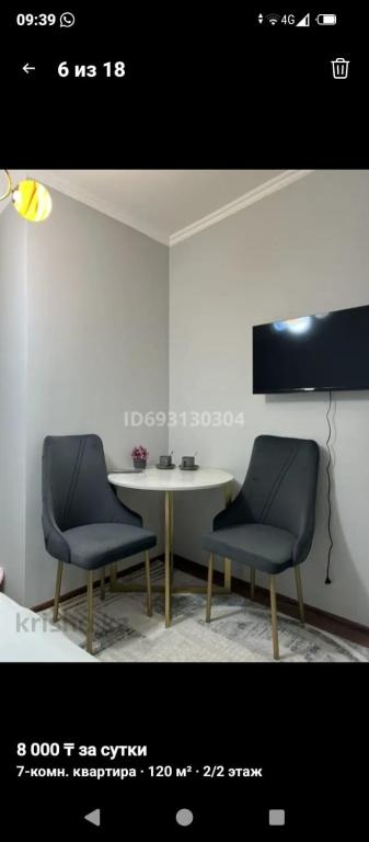 a room with two chairs and a table and a tv at AlmazSabo in Shymkent