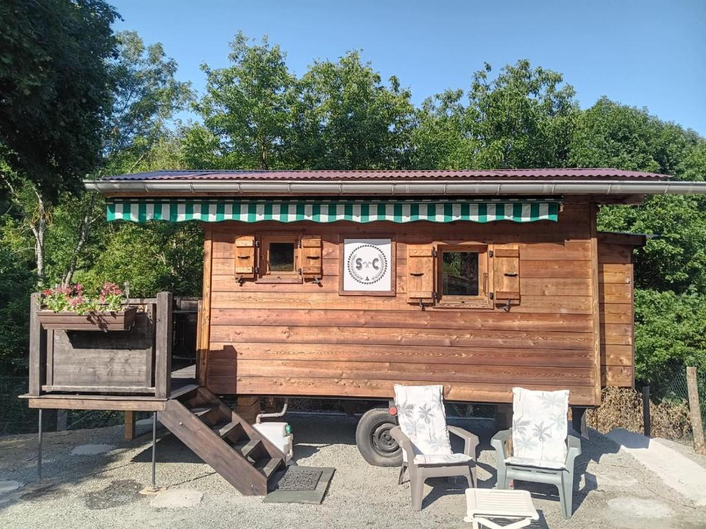 a small wooden house with two chairs and a clock at Notre roulotte de charme in Chevinay