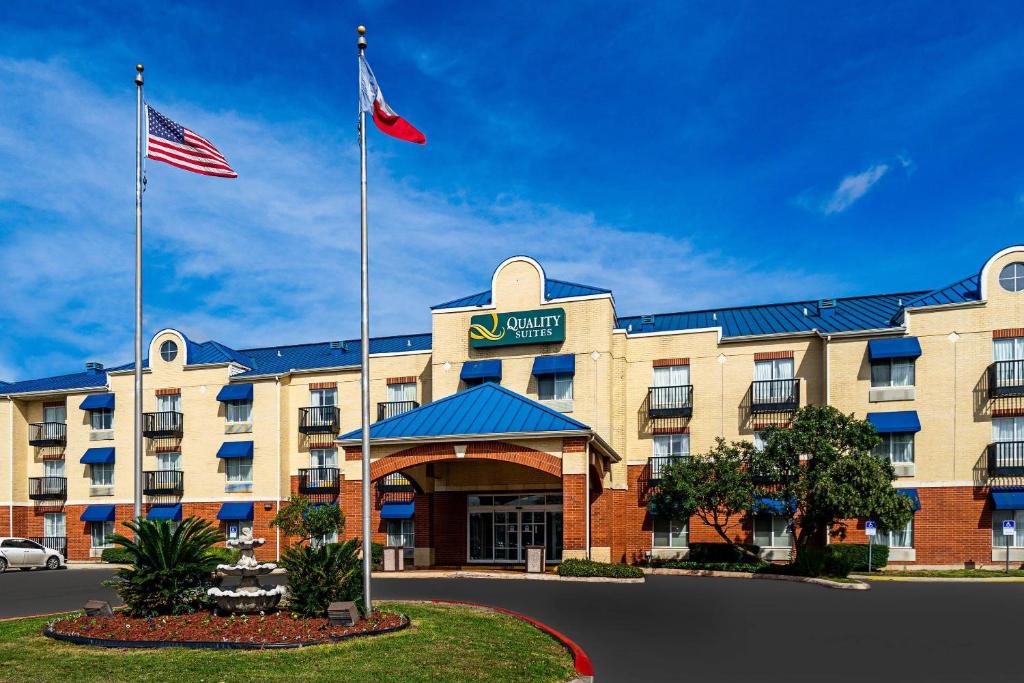 a hotel with two flags in front of it at Quality Suites San Antonio Northeast in San Antonio