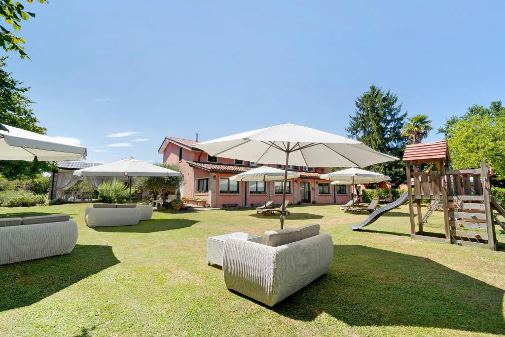 a yard with couches and umbrellas and a playground at Fattoria I Canarini - Biolago in Fossalta di Piave