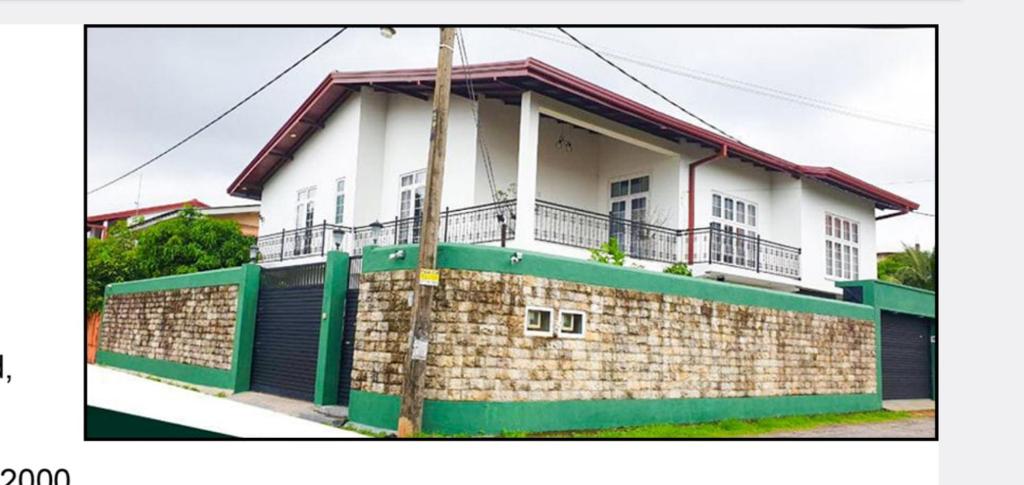 a white and green house with a brick wall at Dee Holidays - in Moratuwa