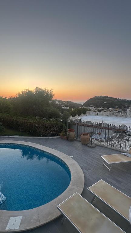 a swimming pool with a sunset in the background at VILLA CLARA ISCHIA piscina riscaldata e idromassaggio in Lacco Ameno