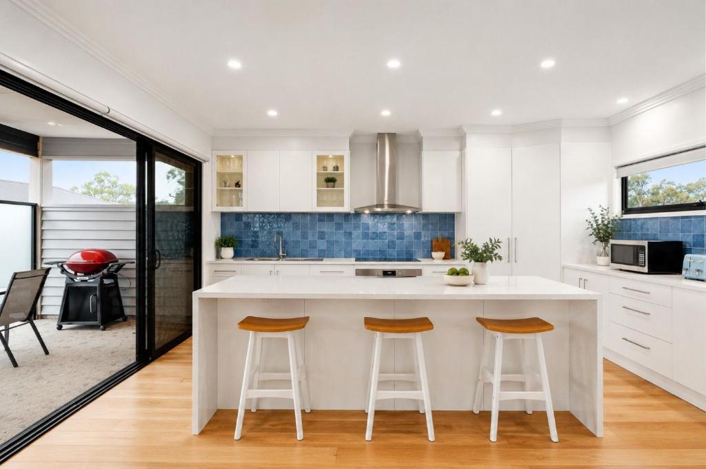 a kitchen with a large white island with two bar stools at Mercer on Port in Portarlington