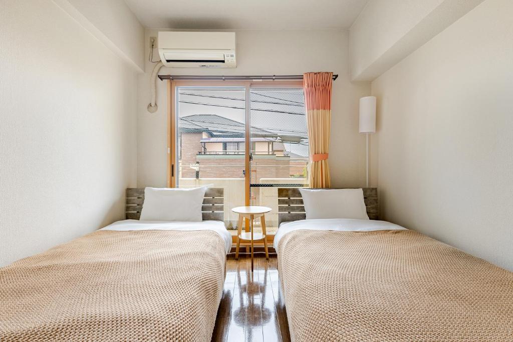 two beds in a room with a window at 大濠ウエストビレッジ209 in Fukuoka