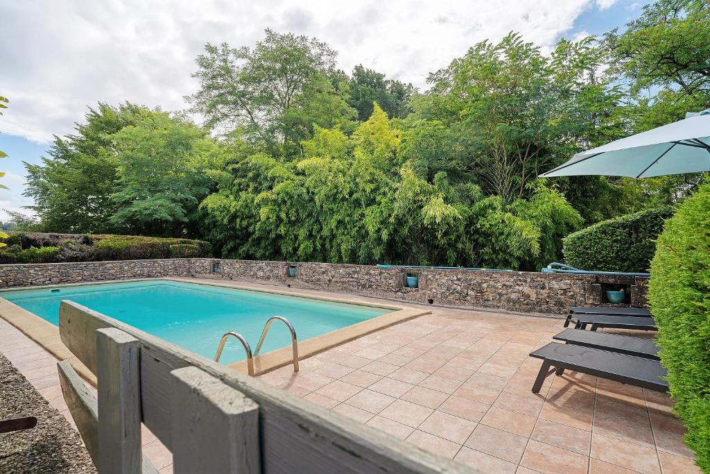 a swimming pool with a bench and an umbrella at Gite Beauséjour in Gaugeac