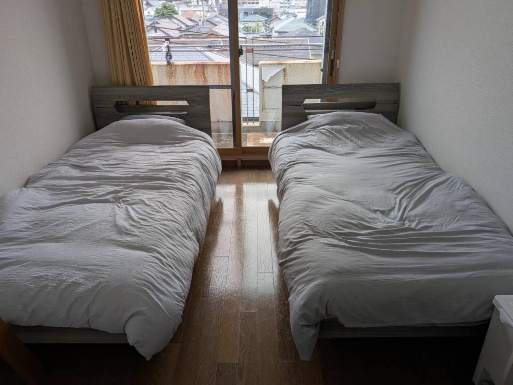 two twin beds in a room with a window at 大濠ウエストヴィレッジ409 in Fukuoka