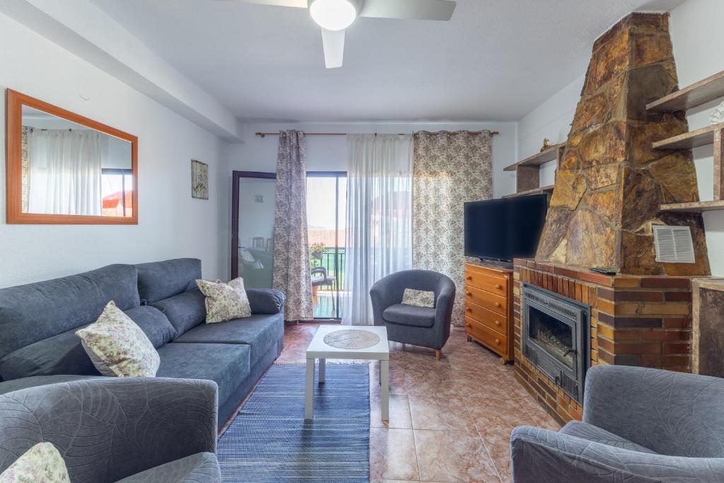 a living room with a blue couch and a fireplace at Vivienda turística El Laurel in Valdemanco