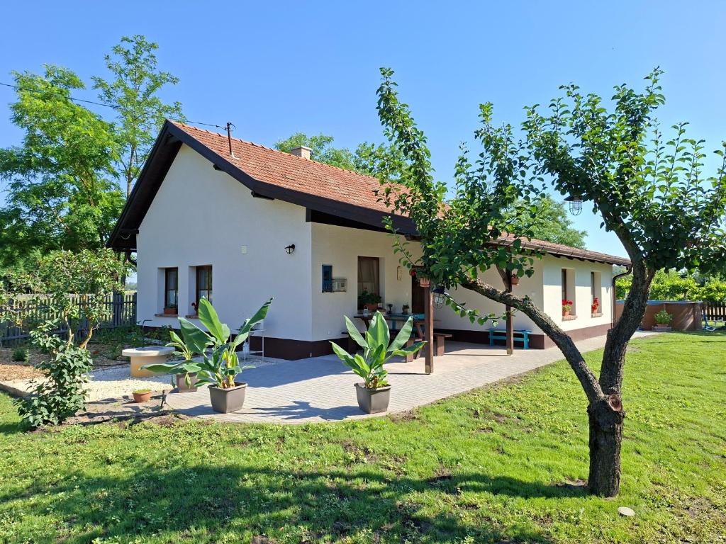 a white house with a tree in front of it at Naprózsa Tanya in Bugac Felső Vasútállomás