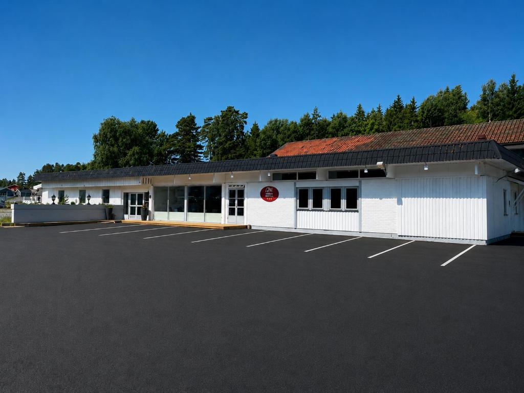 a large white building with a parking lot at Halden Motell in Halden