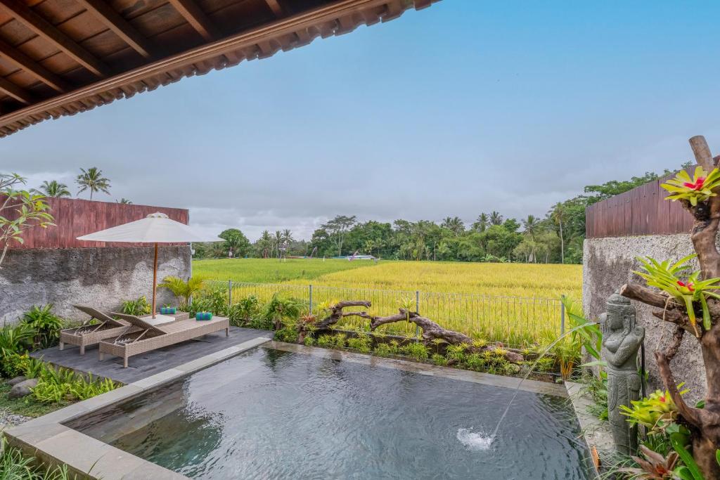 an outdoor pool with a table and an umbrella next to a field at Aranya Ubud Villa in Ubud
