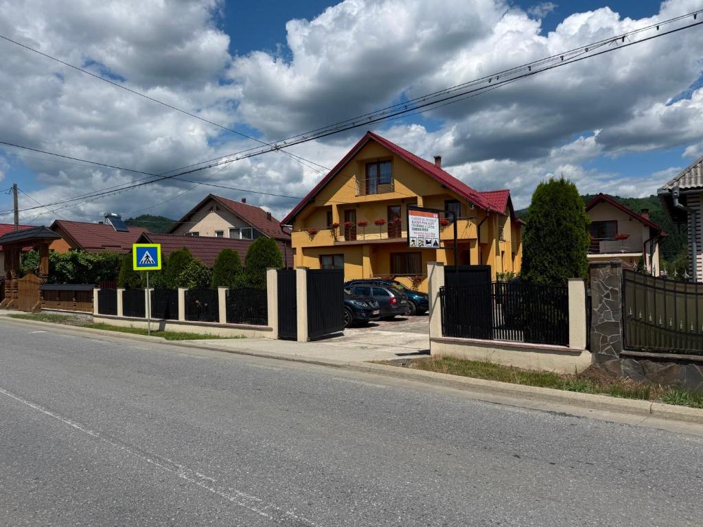 a yellow house on the side of a street at Pensiunea Popan in Şieu