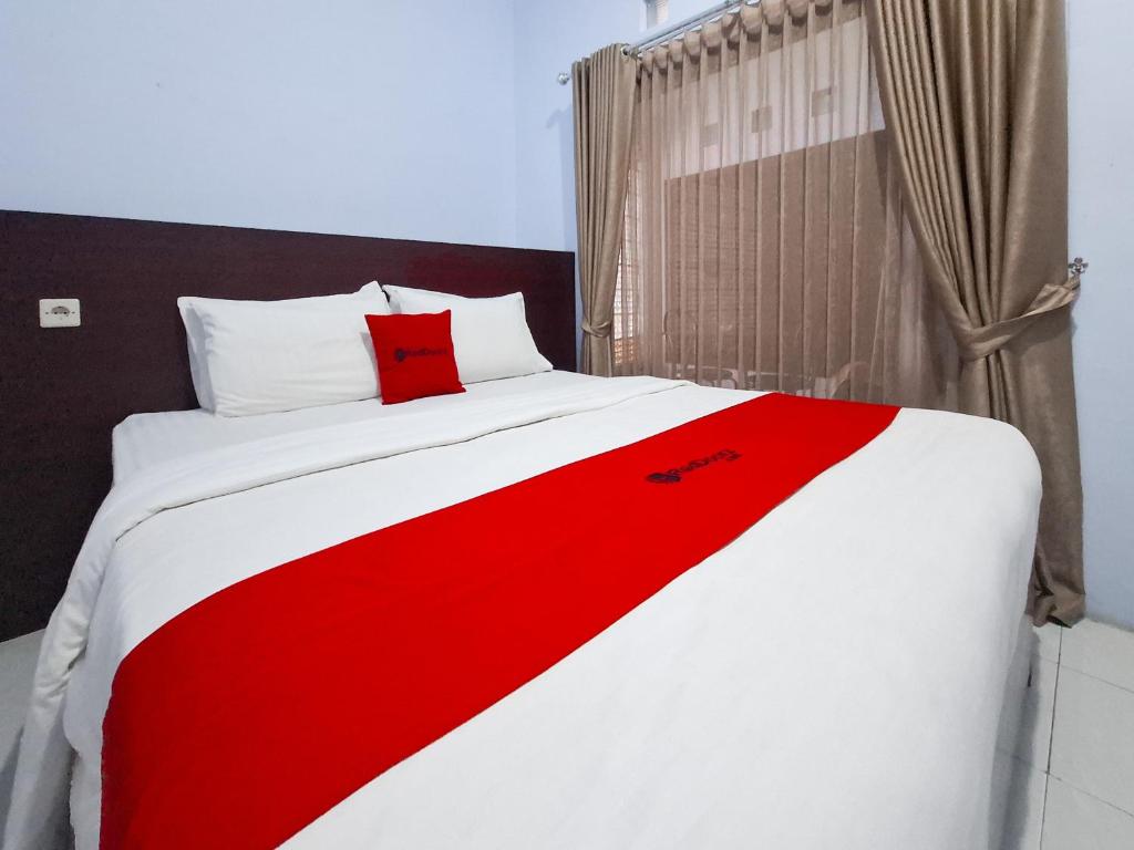 a red and white bed with a red blanket on it at RedDoorz near Ramayana Mall Banyuwangi in Banyuwangi
