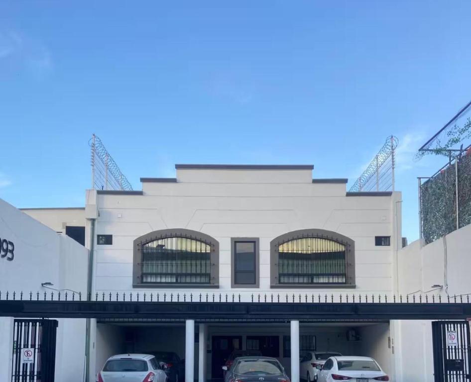 a white building with cars parked in front of it at Barrio Inn Padre Mier Hostal & Suites in Monterrey