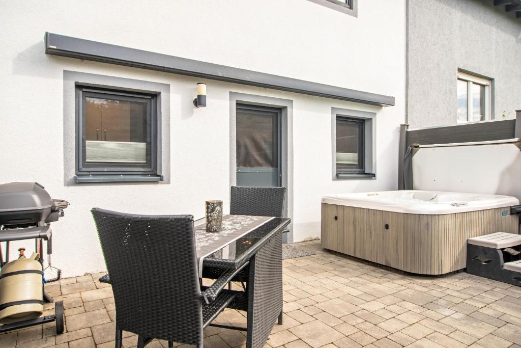a backyard patio with a tub and a grill at Eifel-Dream Kalkmulde in Fleringen