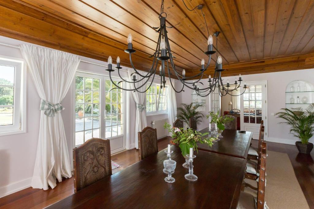 a dining room with a table and a chandelier at Quinta do Cabo Guesthouse in Sintra