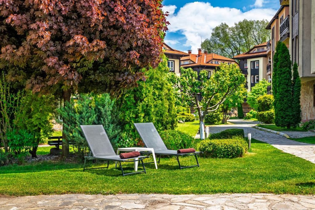 two chairs sitting on the grass in a yard at Hotel Bojur & Bojurland Apartment Complex in Bansko