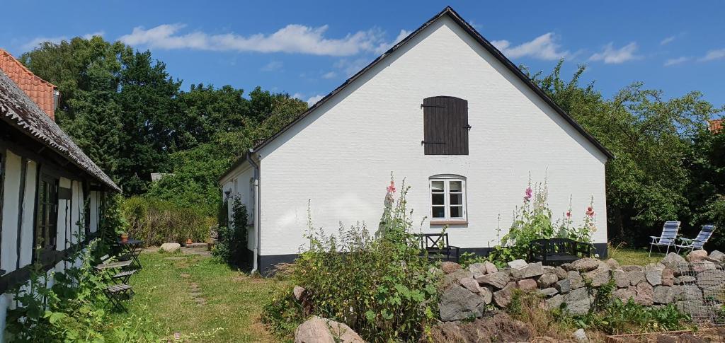 a white barn with a window and a stone wall at Davinde Gæstgiveri in Odense