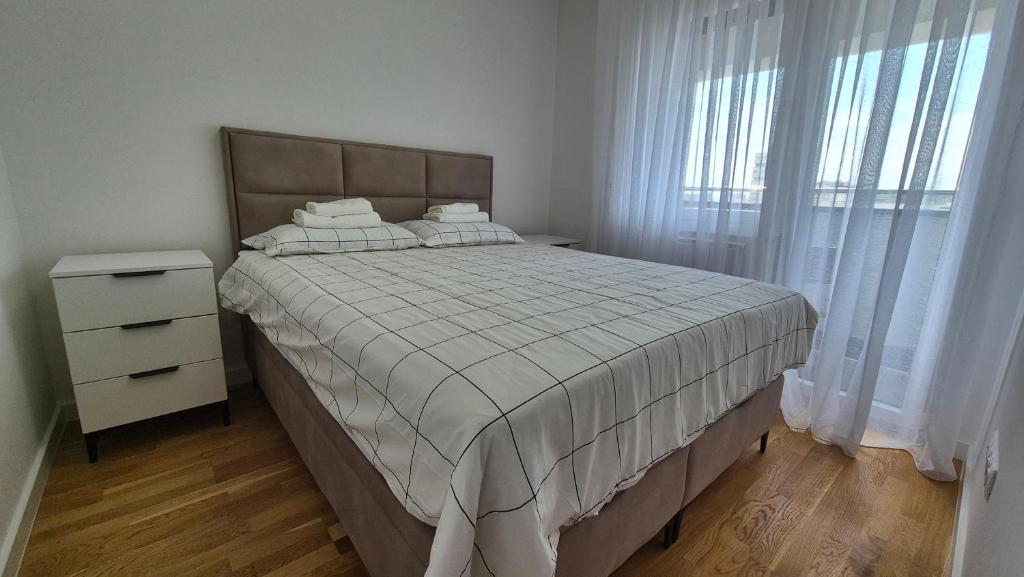 a bedroom with a bed and a dresser and window at MyPlace apartmani 42,56,70 in Tuzla