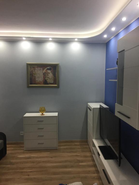 グディニャにあるRiwiera Apartamentの青い壁の客室で、ドレッサー、テレビが備わります。