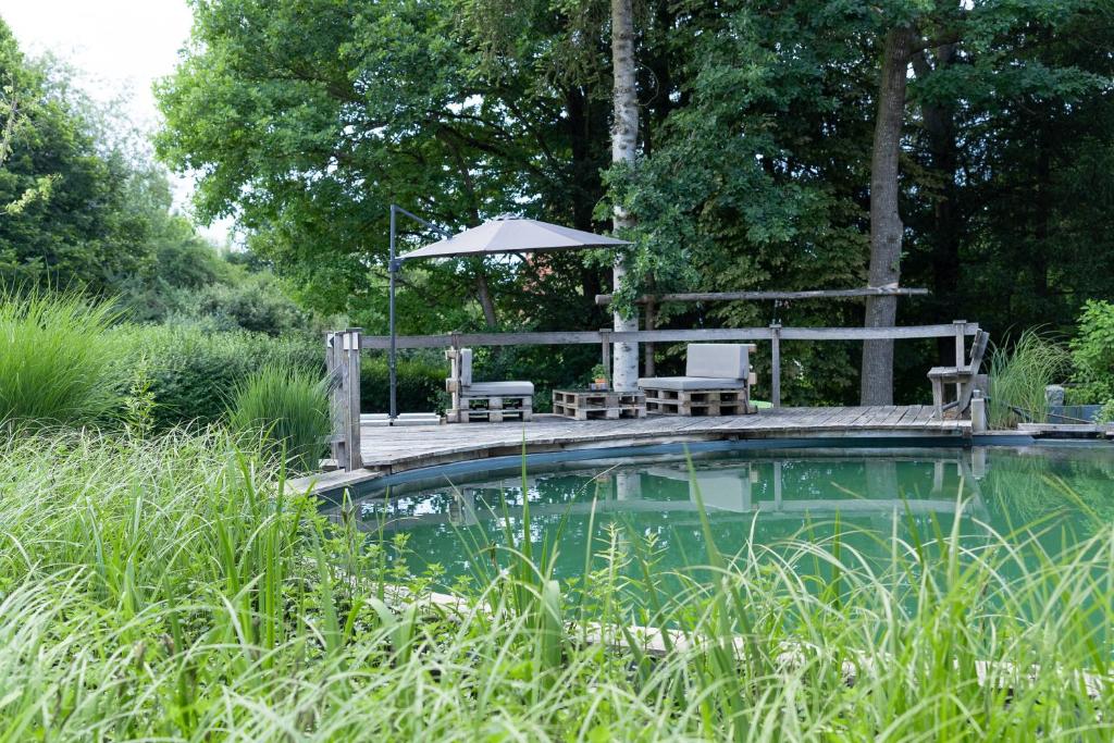 a pool with a table and chairs and an umbrella at Ferienwohnung Donautal in Meßkirch