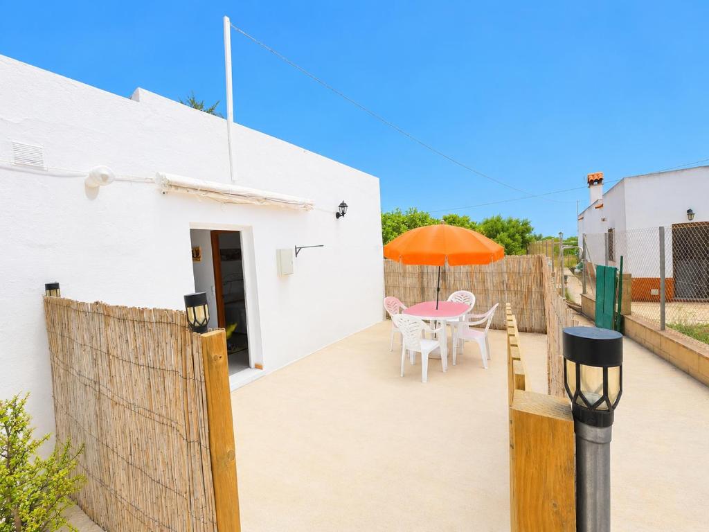 a patio with a table and an orange umbrella at Casa de Los Arbolitos in El Palmar