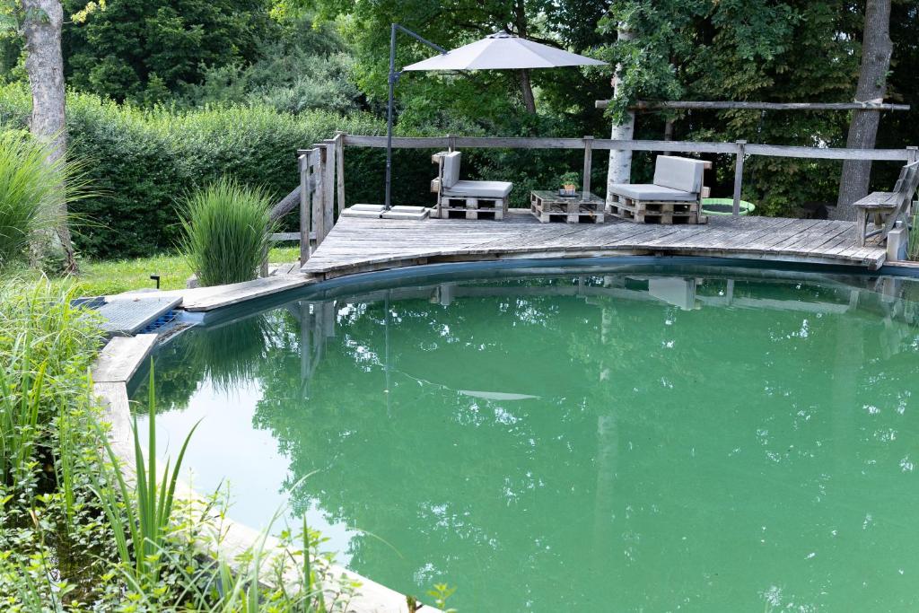 a swimming pool with two chairs and an umbrella at Ferienwohnung Bodensee 2 in Meßkirch