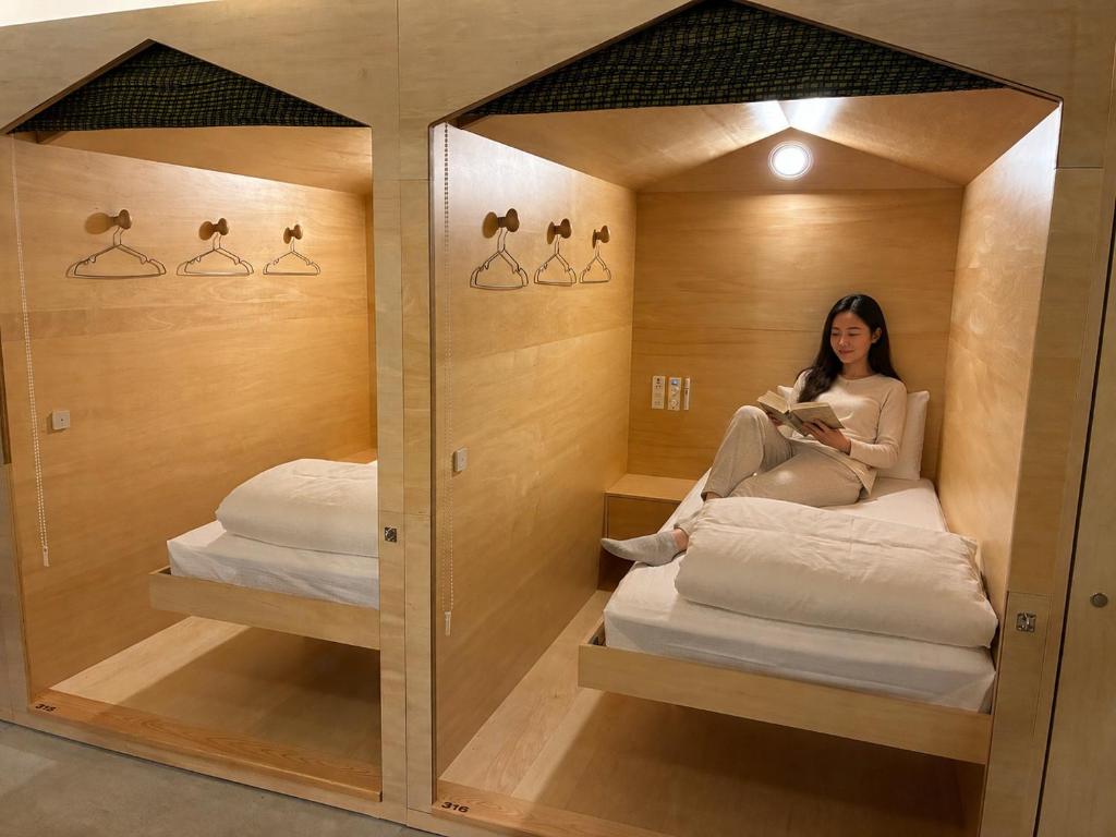 a woman sitting on a chair in a room with a mirror at 女性専用 Woman Only capsule MAJA HOTEL KYOTO マヤホテルキョウト in Kyoto