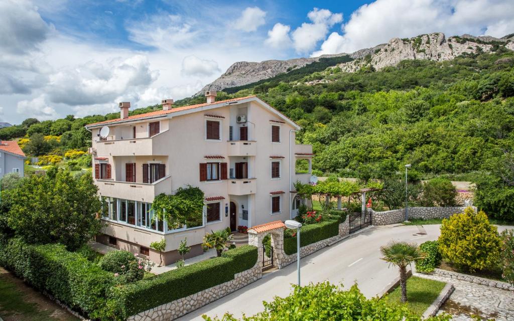 a large white house with a mountain in the background at Apartments Maja and Sanja in Baška