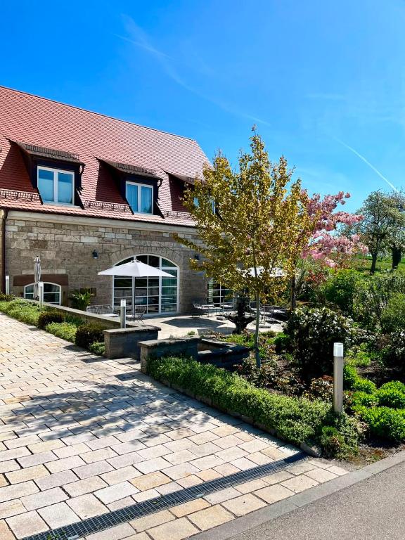 a building with a patio and a tree in front of it at Landhotel Steigenhaus in Untermünkheim