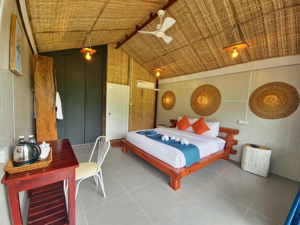 a bedroom with a bed and a table and a desk at Cow Barn Cafe and Lodge Preah Vihear in Phumĭ Nhông
